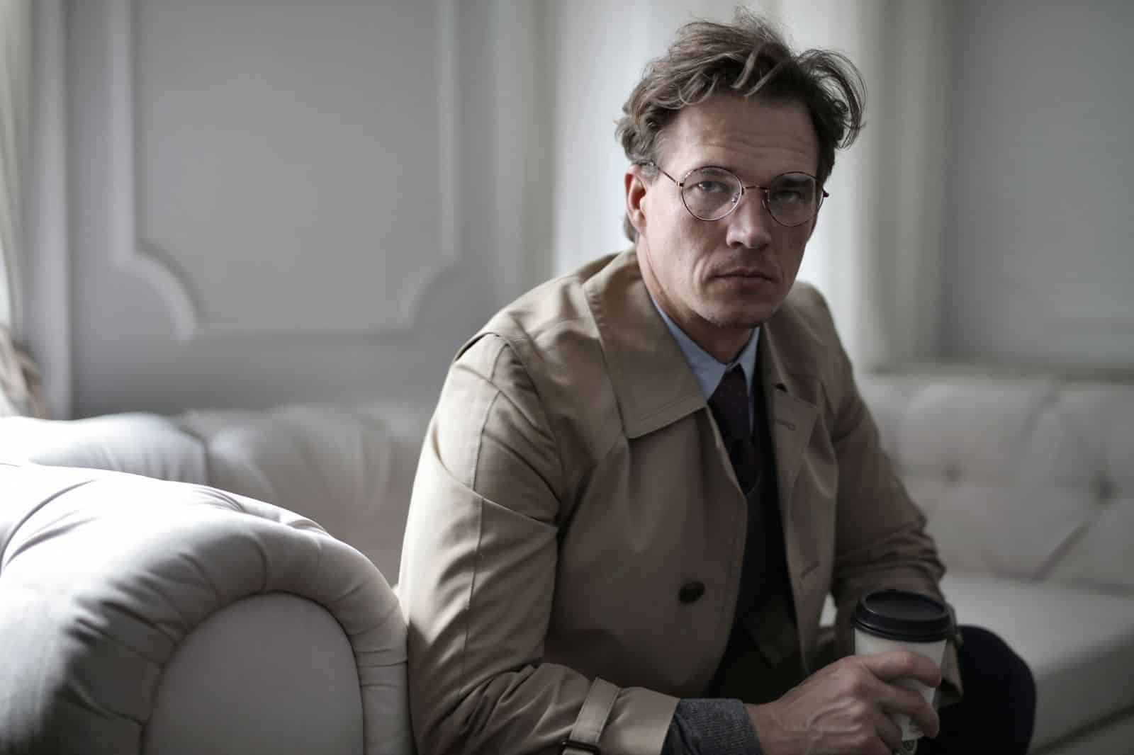 Tired man sitting on a sofa, reflecting Tired man sitting on a sofa, reflecting on symptoms such as low energy