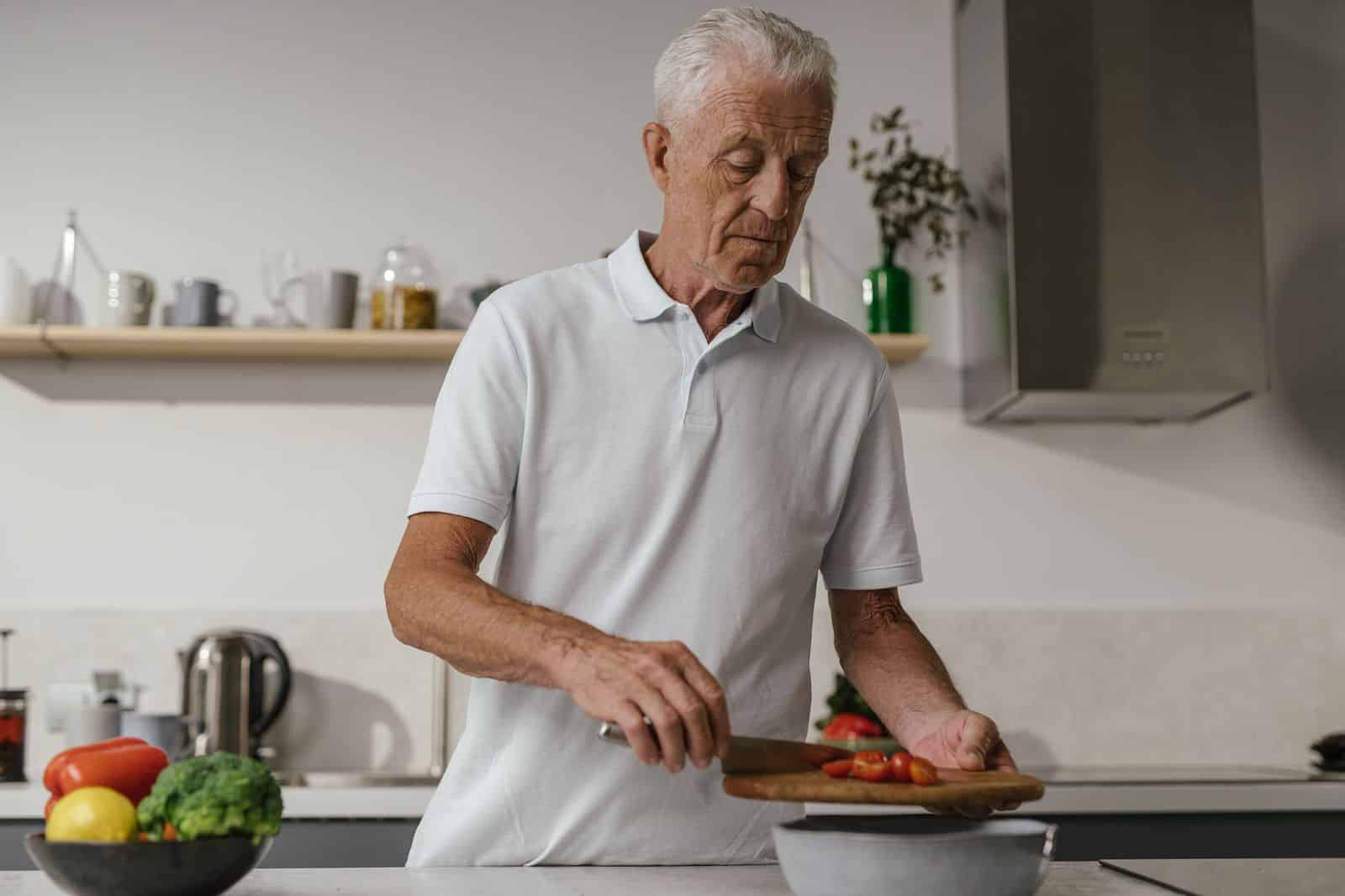 Mature man preparing fresh vegetables for a Mature man preparing fresh vegetables for a healthy meal at home