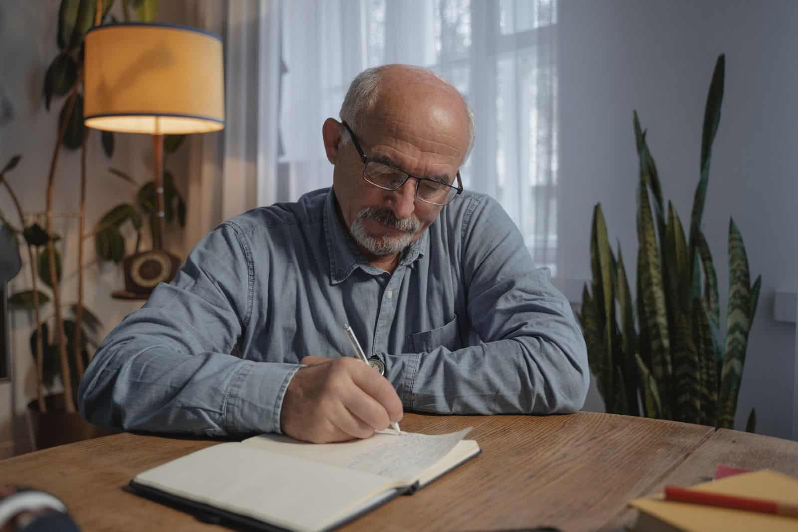 Mature man writing notes at home to Mature man writing notes at home to prepare for a weight-loss consultation